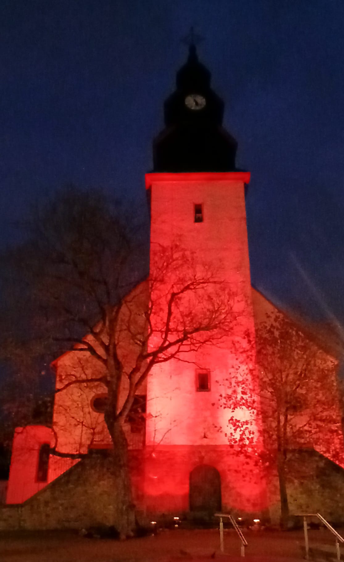 Glockenturm der St.-Remigius-Kirche Ober-Mörlen rot beleutet