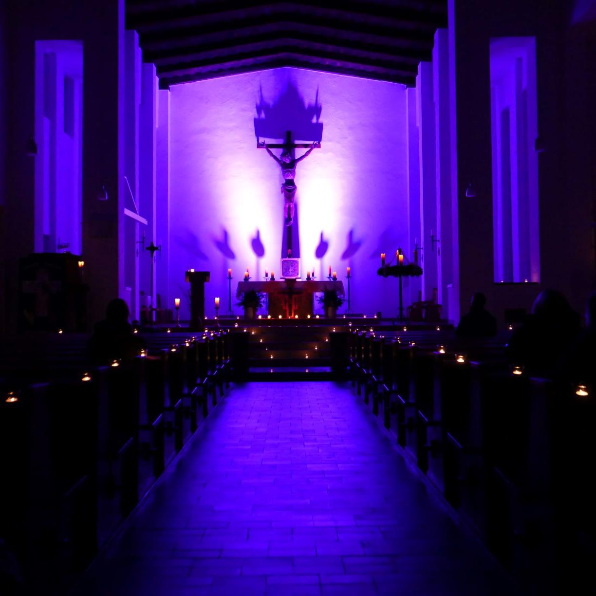 Blick in die dunkle, von Kerzen in lila Licht getauchte Sankt Gottfriedskirche