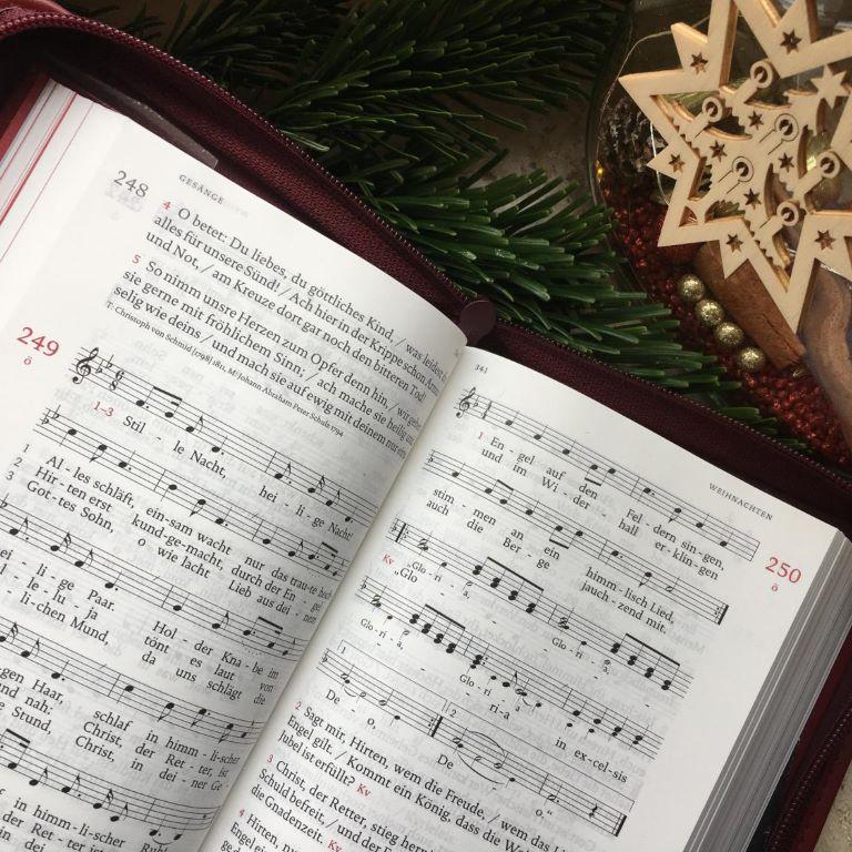 Aufgeschlagenes Gotteslob neben Weihnachtsdeko