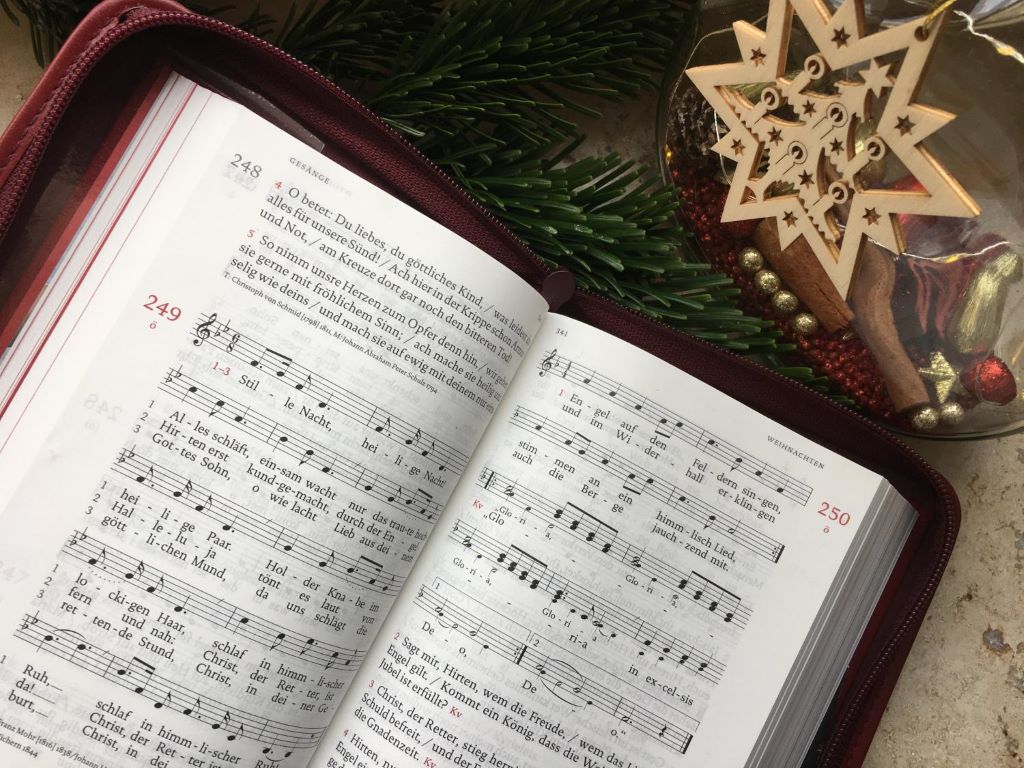 Aufgeschlagenes Gotteslob neben Weihnachtsdeko