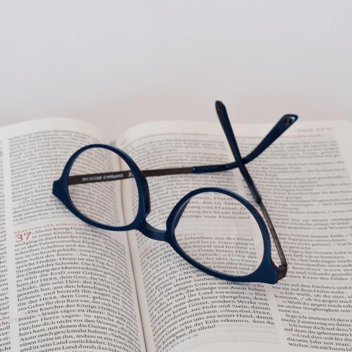 offenes Buch mit darauf liegender Brille