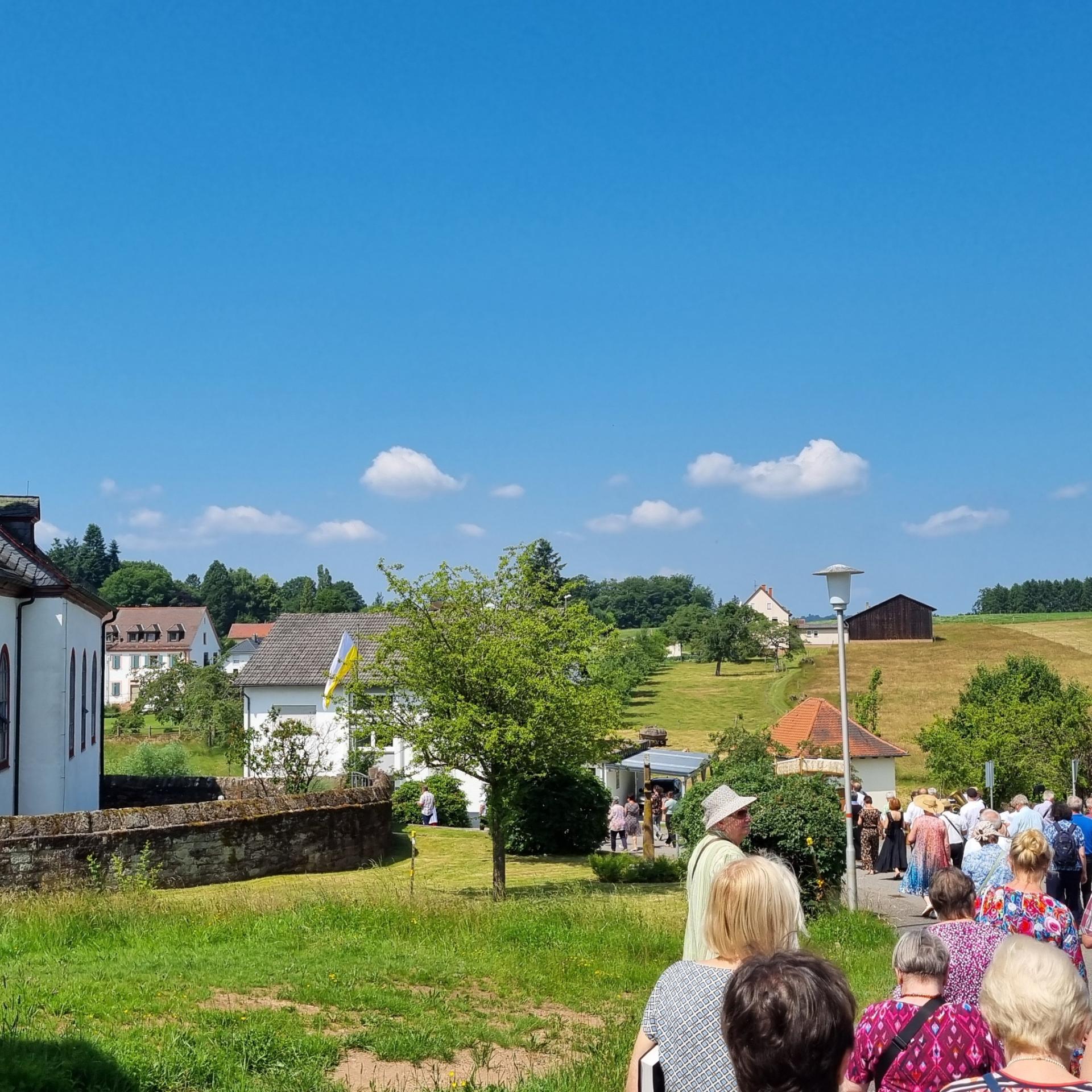 Menschen ziehen an der Dorfkirche Hesselbach vorbei