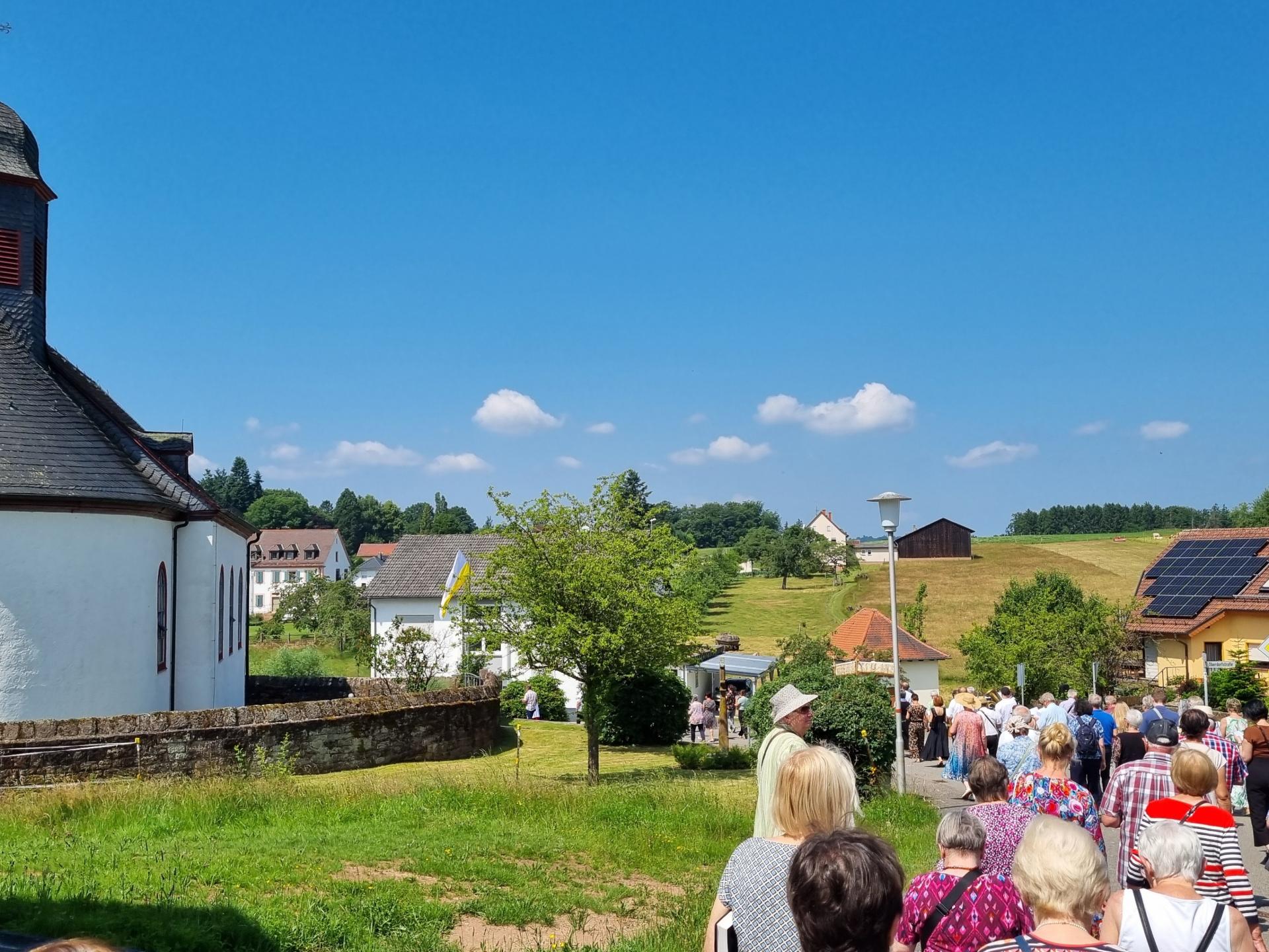 Menschen ziehen an der Dorfkirche Hesselbach vorbei