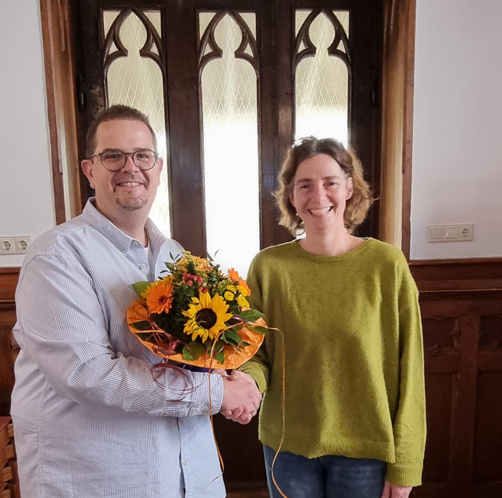 Grüß' Gott mit Blumen! Verwaltungsleiter Matthias Kusch begrüßt Kirsten Molitor. (c) Pastoralraum Odenwaldkreis/WW