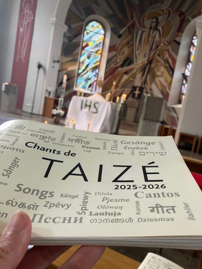 Taize-Liederheft im Vordergrund mit Blick auf die Apsis mit Monstranz