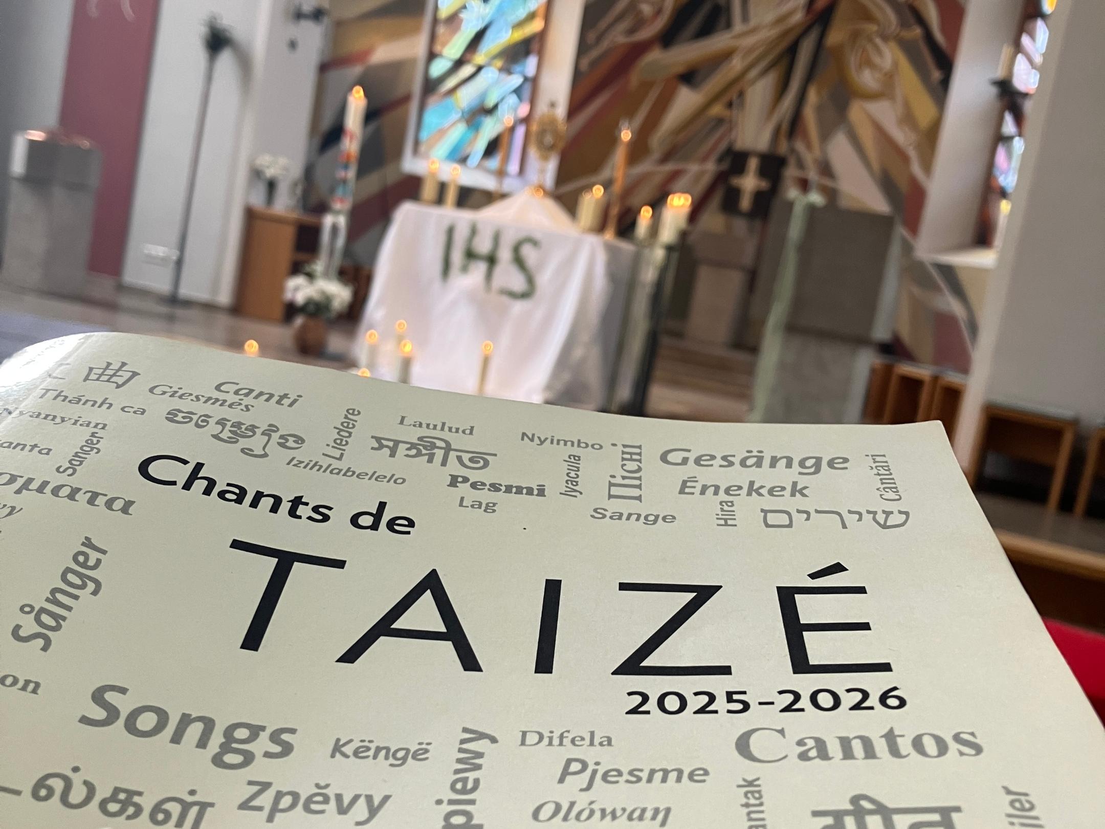 Taize-Liederheft im Vordergrund mit Blick auf die Apsis mit Monstranz