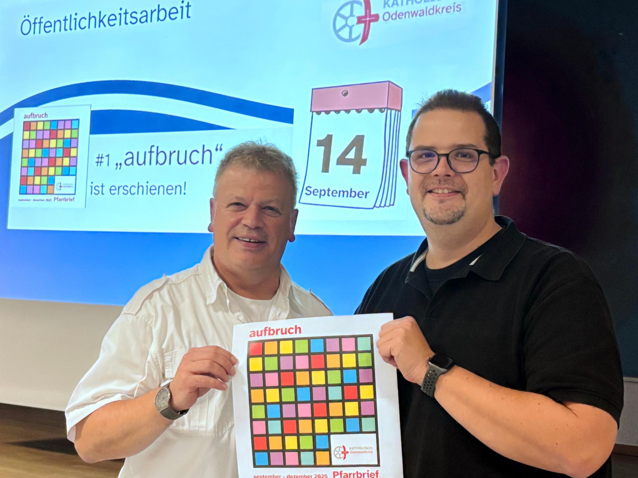Leitender Pfarrer Harald Poggel und Verwaltungsleiter Matthias Kusch vor Projektionswand zeigen das Titelblatt des neuen Pfarrbriefs