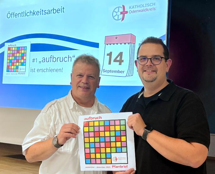 Leitender Pfarrer Harald Poggel und Verwaltungsleiter Matthias Kusch vor Projektionswand zeigen das Titelblatt des neuen Pfarrbriefs