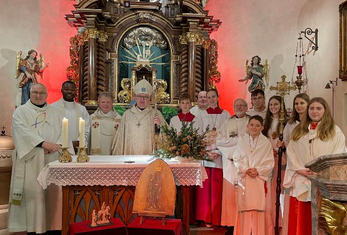 .l.: Diakon Volkmar Raabe, Kaplan Cornelius Agbo, Leitender Pfarrer Harald Poggel, Bischof Peter Kohlgraf, Pfarrer Jozef Koscielny, Pfarrer i.R. Januarius Mäurer und Messdienern aus Hesselbach, Beerfelden, Vielbrunn und Lützelbach – Vordergrund Bildnis der Schwarzen Madonna des Odenwaldes und der kleinen Statue des heiligen Martin