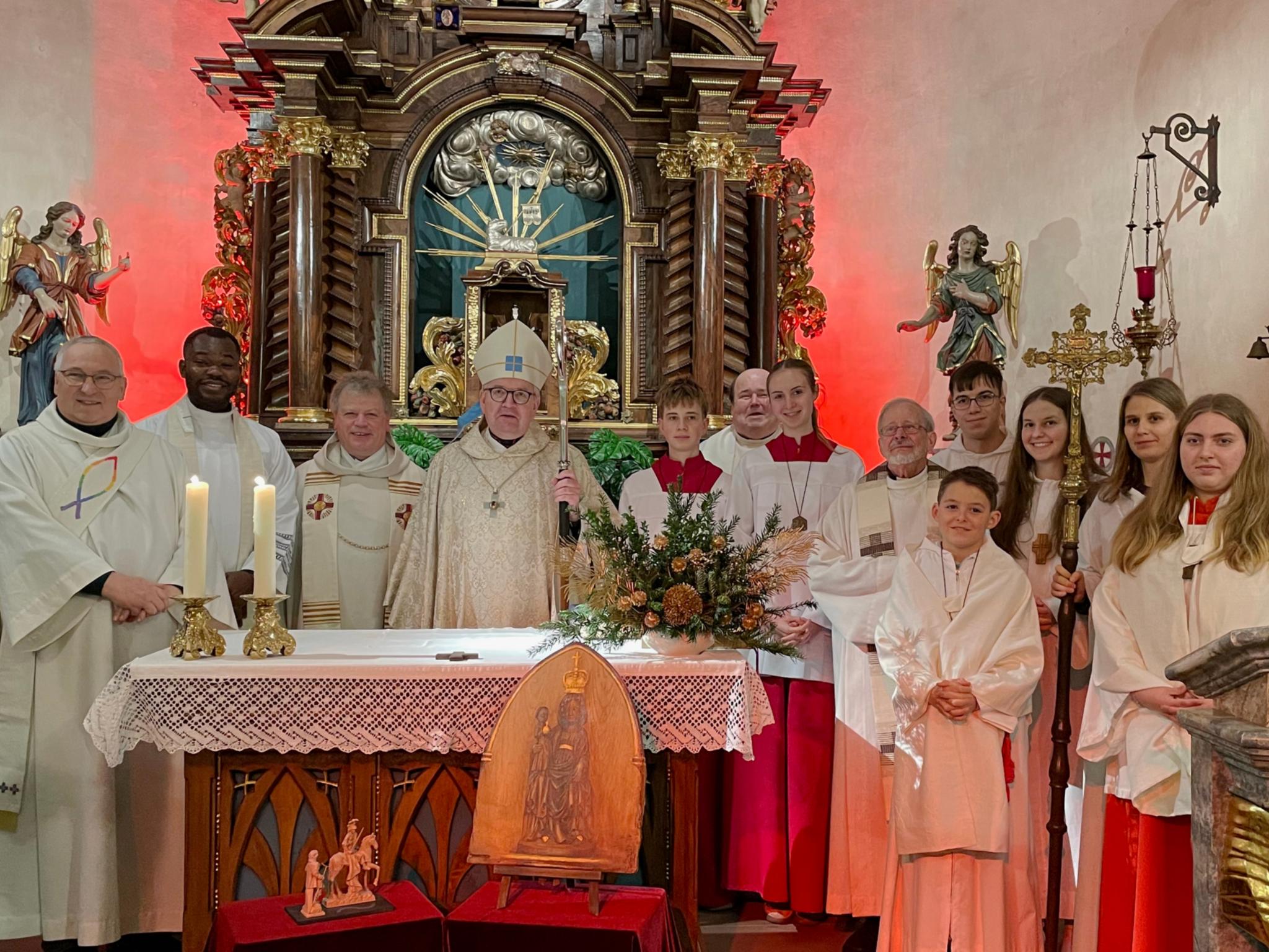 .l.: Diakon Volkmar Raabe, Kaplan Cornelius Agbo, Leitender Pfarrer Harald Poggel, Bischof Peter Kohlgraf, Pfarrer Jozef Koscielny, Pfarrer i.R. Januarius Mäurer und Messdienern aus Hesselbach, Beerfelden, Vielbrunn und Lützelbach – Vordergrund Bildnis der Schwarzen Madonna des Odenwaldes und der kleinen Statue des heiligen Martin