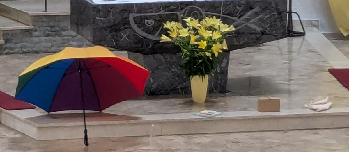 Regenschirm, kleine Flasche Weihwasser, Mauerstein, Tasche liegen vor dem Altar (c) up