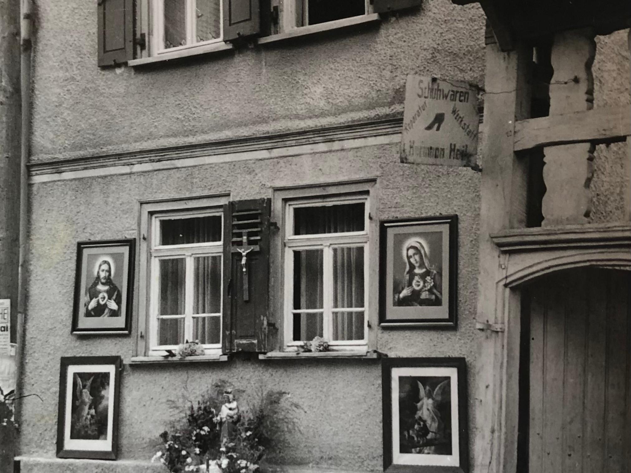 Haus mit blumengeschmücktem Hausaltar davor
