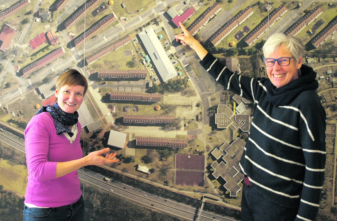 Blick von oben: Ingrid Erdmann und Petra Elmer (von links) zeigen auf der Karte, wo sie ihr Büro in einer ehemaligen Tankstelle haben. | Foto: Sara Mierzwa (c) Kirchenzeitung Glaube und Leben