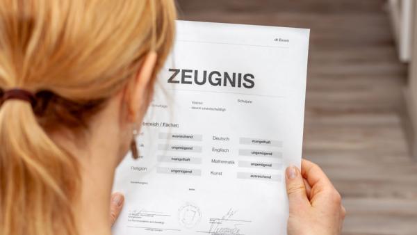 Frau liest ein Schulzeugnis