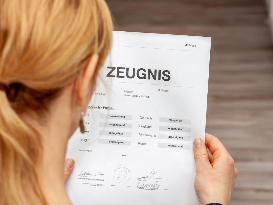 Frau liest ein Schulzeugnis