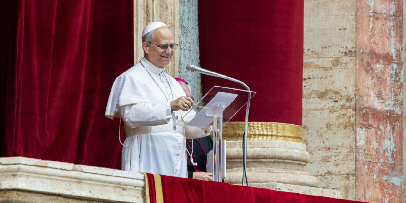 Freundlich lächelnder Papst Leo XIV. in weißer Soutane auf der Loggia über dem Petersplatz