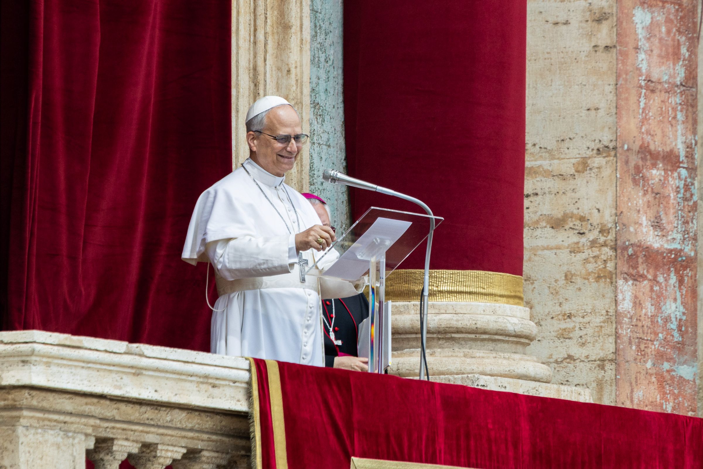 Freundlich lächelnder Papst Leo XIV. in weißer Soutane auf der Loggia über dem Petersplatz