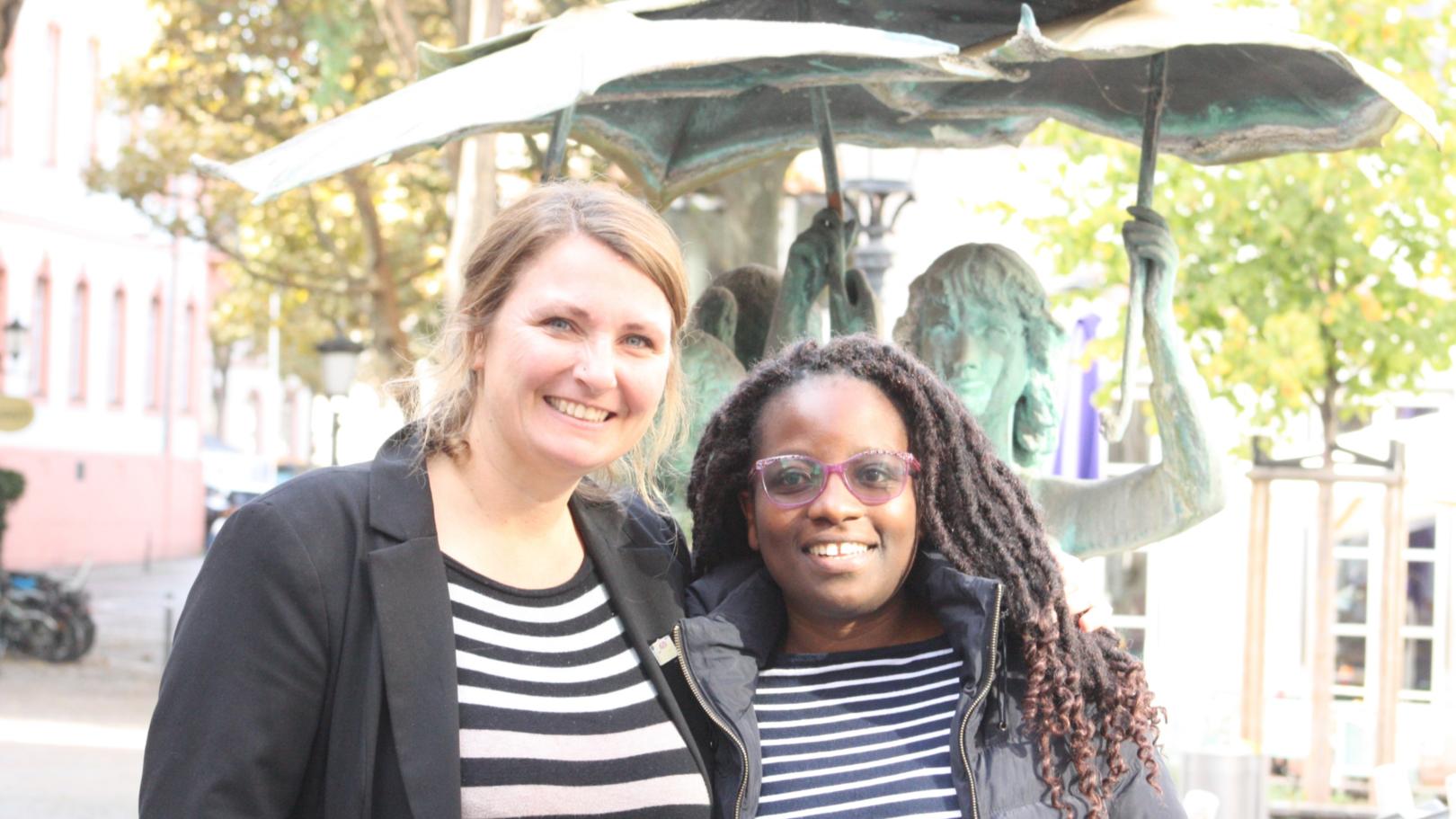 Missio-Gast aus Kenia unterwegs in den Bistümern Fulda, Limburg und Mainz: Paula Kidakwa (rechts), hier mit der Mainzer Missio-Referentin Dr. Eva Baillie am „Drei-Mädchen-Brunnen“ an der Maria Ward-Schule in Mainz. (c) Kirchenzeitung/ Anja Weiffen