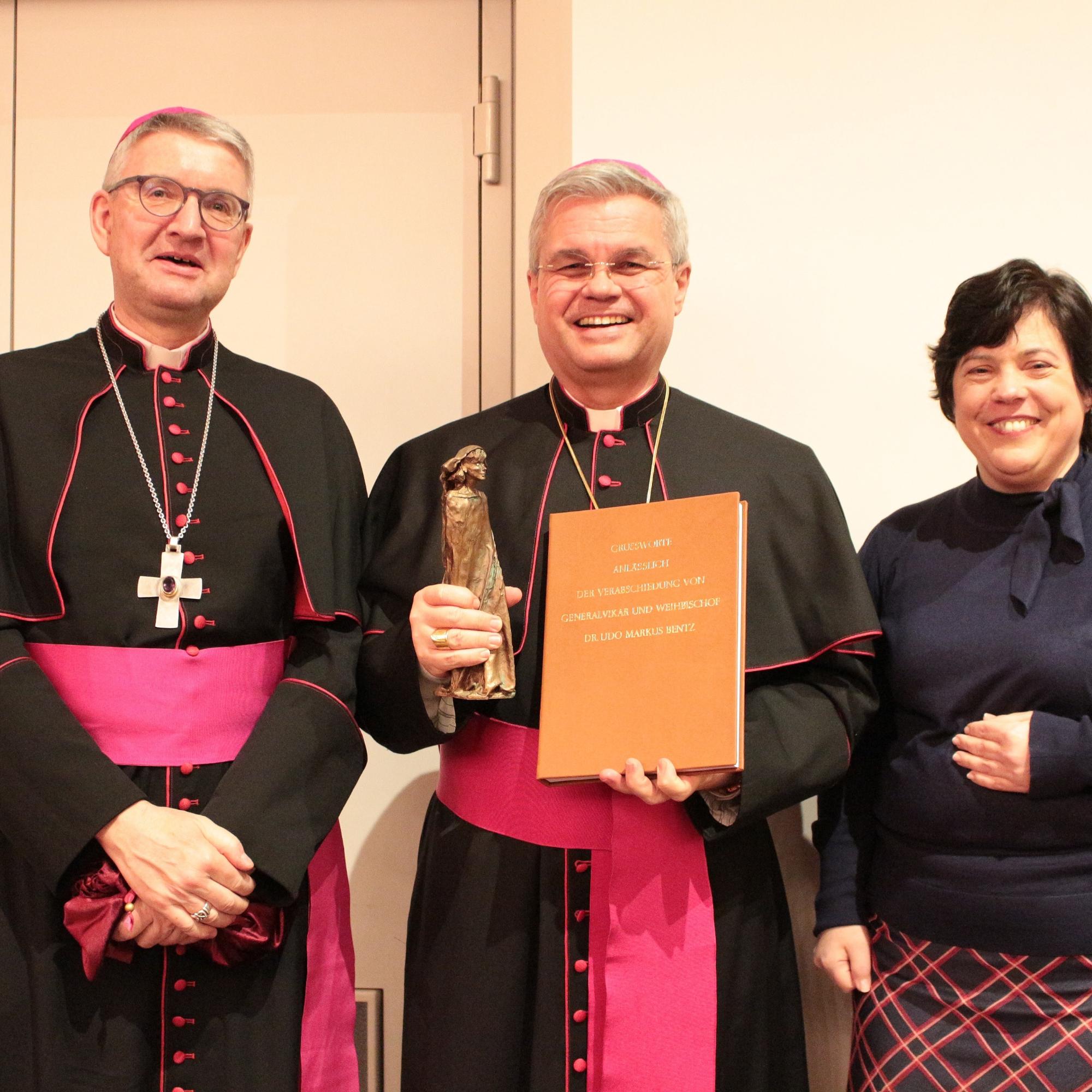 Mainz, 18. Februar 2024: Bischof Peter Kohlgraf überreichte gemeinsam mit Stephanie Rieth (rechts) die Geschenke des Bistums an den scheidenden Weihbischof Udo Markus Bentz (Mitte).