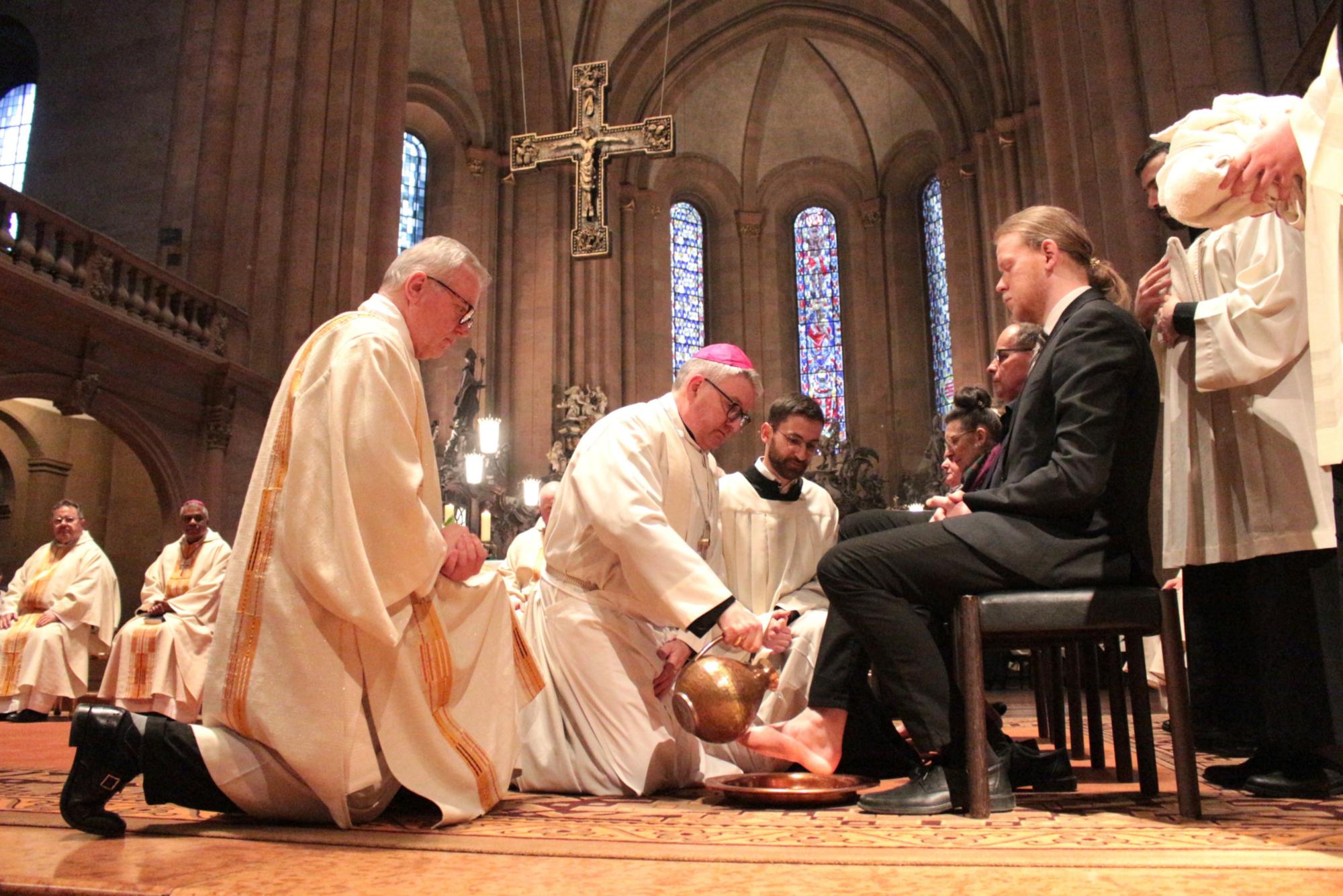 Mainz, 2. April 2026: Der Mainzer Bischof Peter Kohlgraf bei der Fußwaschung im Mainzer Dom; assistiert von Diakon Professor Helmut Pulte (links) und dem Mainzer Seminaristen Joseph Möller (rechts).