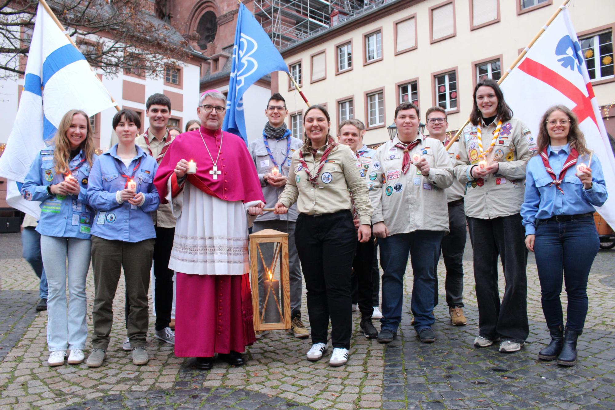 Mainz, 15. Dezember 2024: Bischof Peter Kohlgraf mit Pfadfinderinnen und Pfadfindern, die das Friedenslicht verteilen werden, auf dem Mainzer Leichhof. (c) Bistum Mainz / Blum