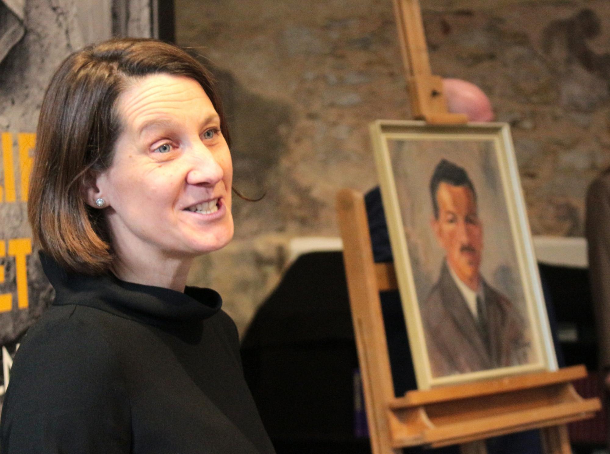 Mainz, 11. Dezember 2025: Mit drei Geschichten aus ihrem Werdegang berichtete Dr. Anja Lempges von ihrem Selbstverständnis; im Hintergrund ist ein Gemälde ihres Urgroßvaters Nikolaus aus dem Jahr 1925 zu sehen, in dessen Haus in der Eifel sie aufgewachsen ist. (c) Bistum Mainz / Blum