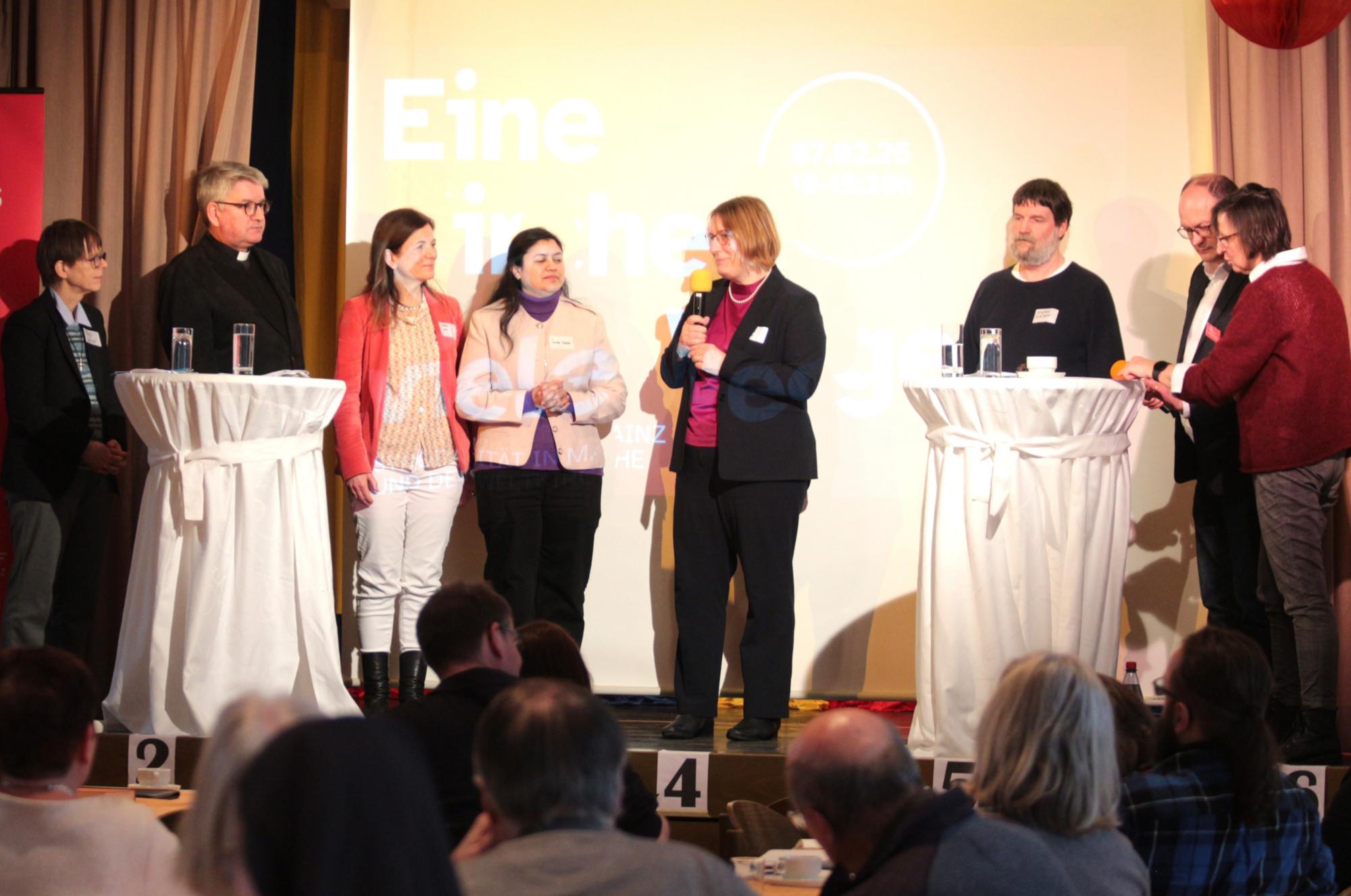 Mainz, 7. Februar 2026: Auf der Bühne des Kolpinghauses (v.l.n.r.): Schwester Birgit Weiler, Bischof Peter Kohlgraf, Meike Jolie Sana Iqbal, Regina Heyder Stephan Weidner, Andreas Linsenmann und Renate Flath.