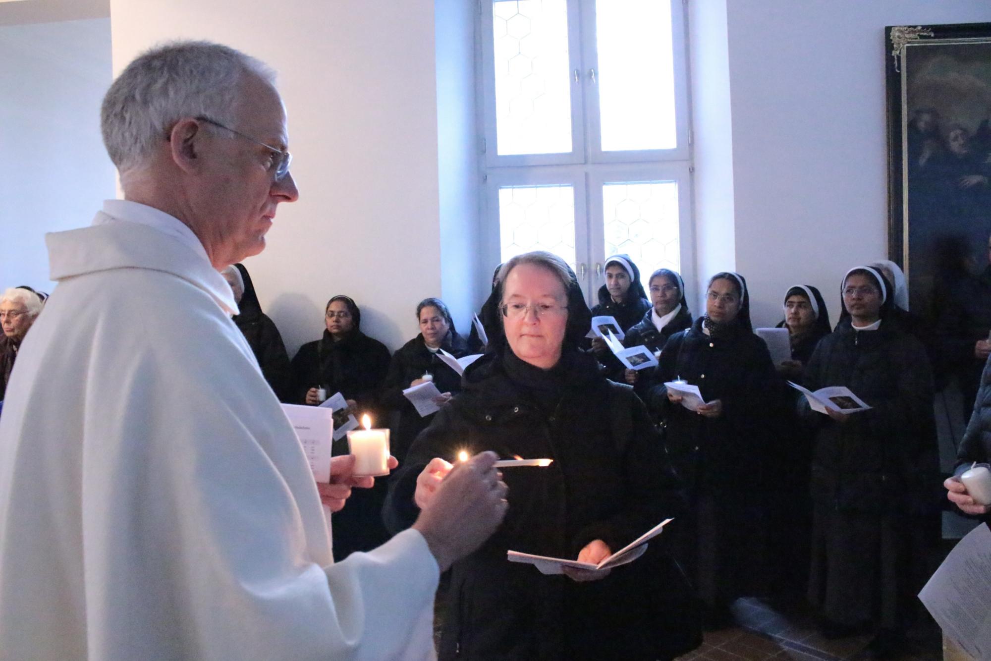 Mainz, 2. Februar 2024: Domkapitular Hans-Jürgen Eberhardt gibt das Licht vor der Prozession an Schwester Mary Angela Alexander RSM vom Vorstand des Ordensrates weiter. (c) Bistum Mainz / Blum