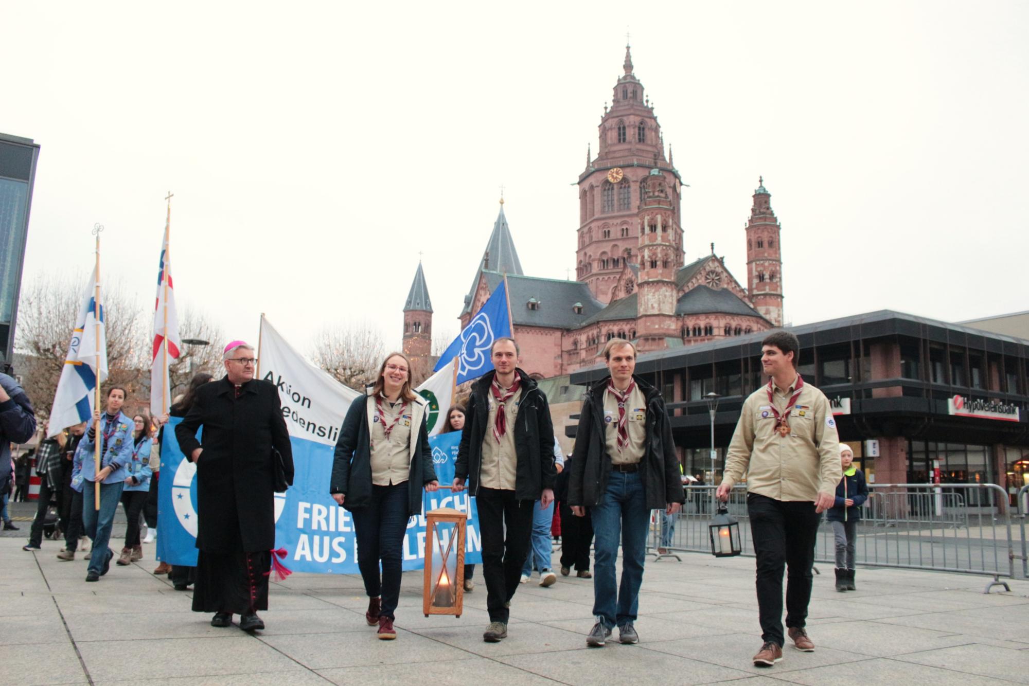 Mainz, 14. Dezember 2025: Bischof Peter Kohlgraf (links vorne) begleitete die Darmstädter Delegation mit dem Friedenslicht aus Bethlehem zusammen mit Johannes Blüm (vorne rechts) zum Abschluss vor dem Mainzer Staatstheater. (c) Bistum Mainz / Blum