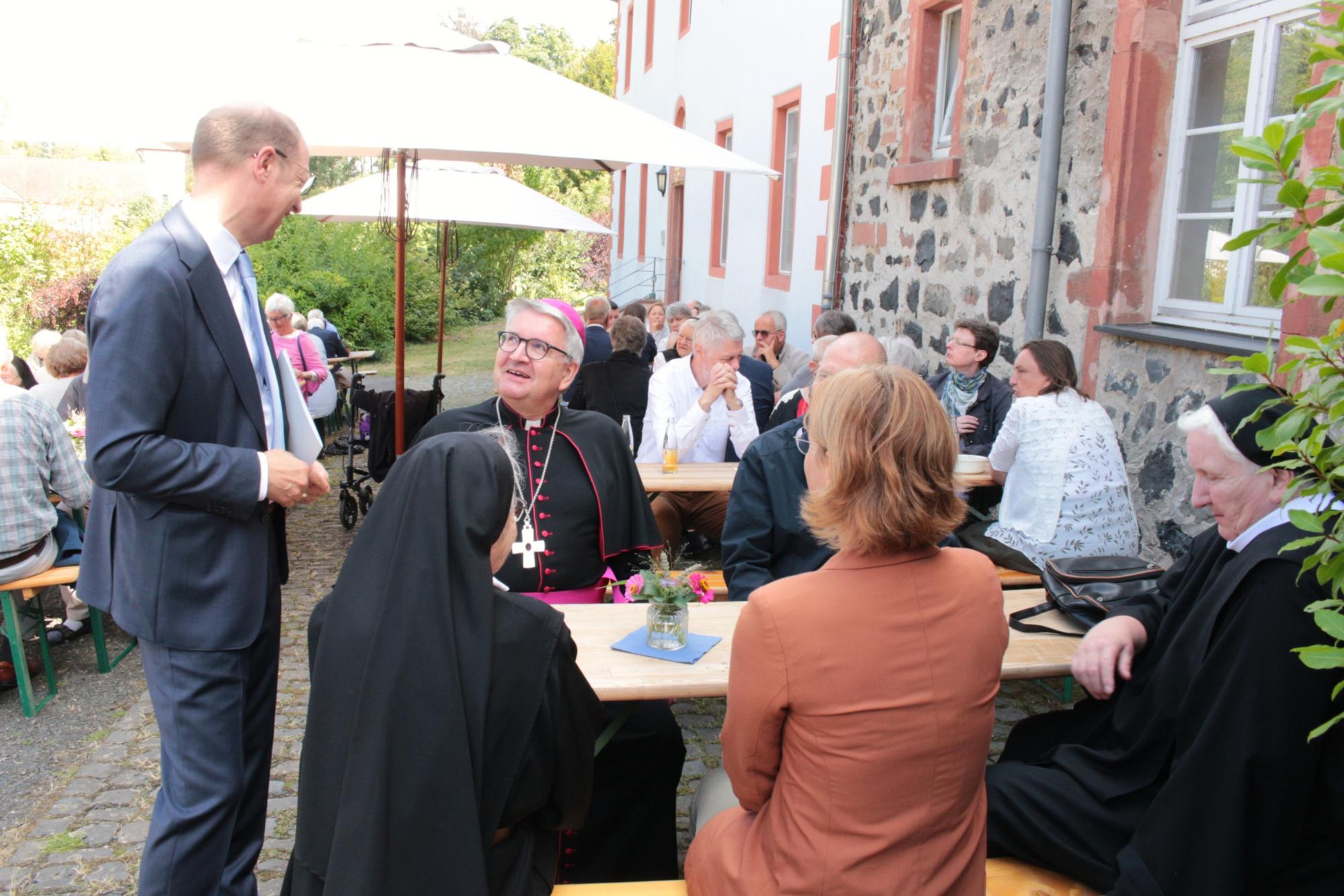 Altenstadt, 23. August 2026: Bischof Peter Kohlgraf im Gespräch mit Landrat Jan Weckler (stehend) nach dem Verabschiedungsgottesdienst.