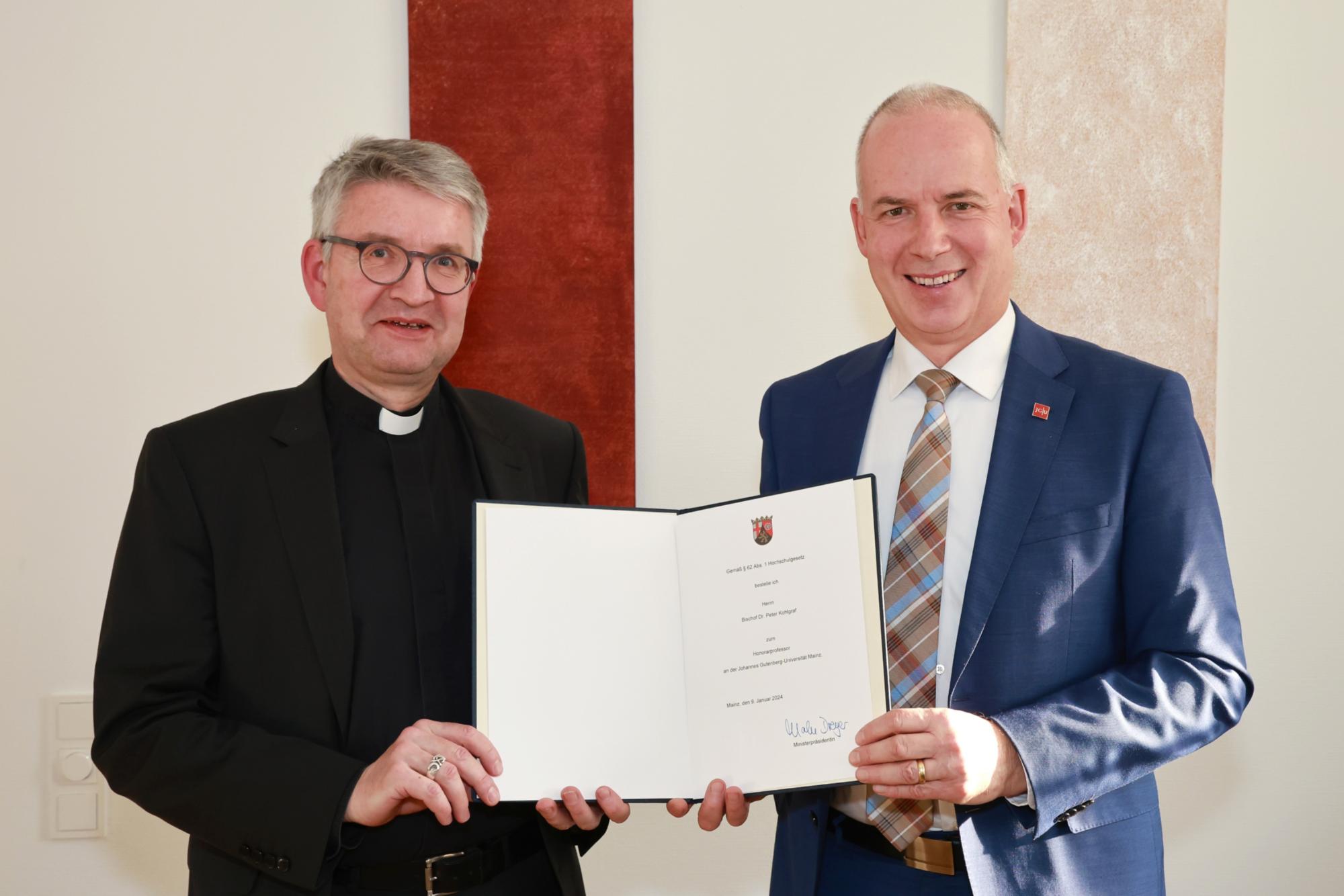 Bischof Peter Kohlgraf erhält die Ernennungsurkunde zum Honorarprofessor der Johannes Gutenberg-Universität Mainz vom Präsidenten der Universität, Georg Krausch