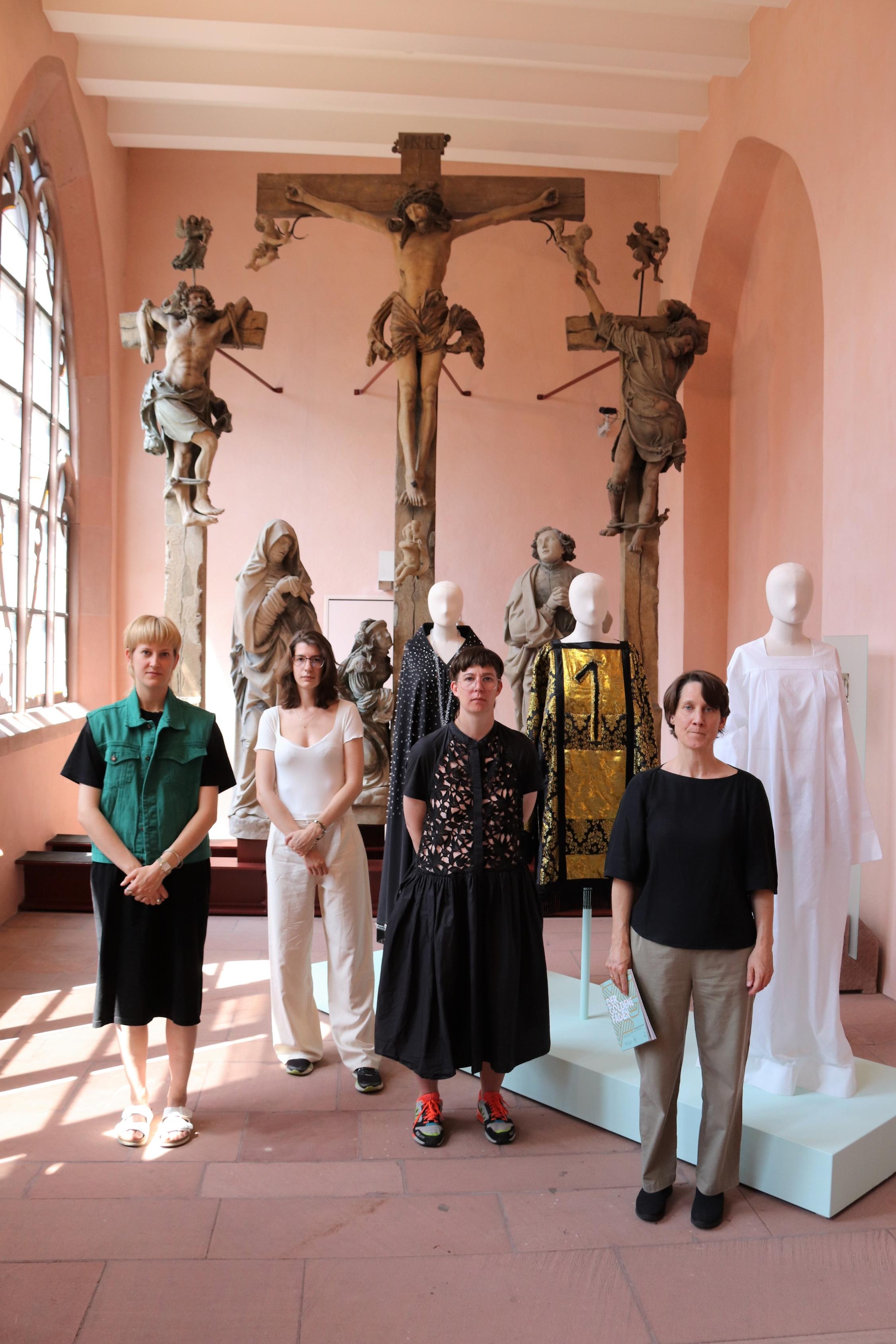 Mit dem Thema Missbrauch in der katholischen Kirche setzt sich die Kollektion von Yvonne von Brandis (Zweite von links) auseinander. Ganz links im Bild steht ihre Kommilitonin Hanna Oschmann, rechts daneben Professorin Ilona Kötter, ganz rechts im Bild Dr. Anja Lempges, stellvertretende Leiterin des Mainzer Dom- und Diözesanmuseums.