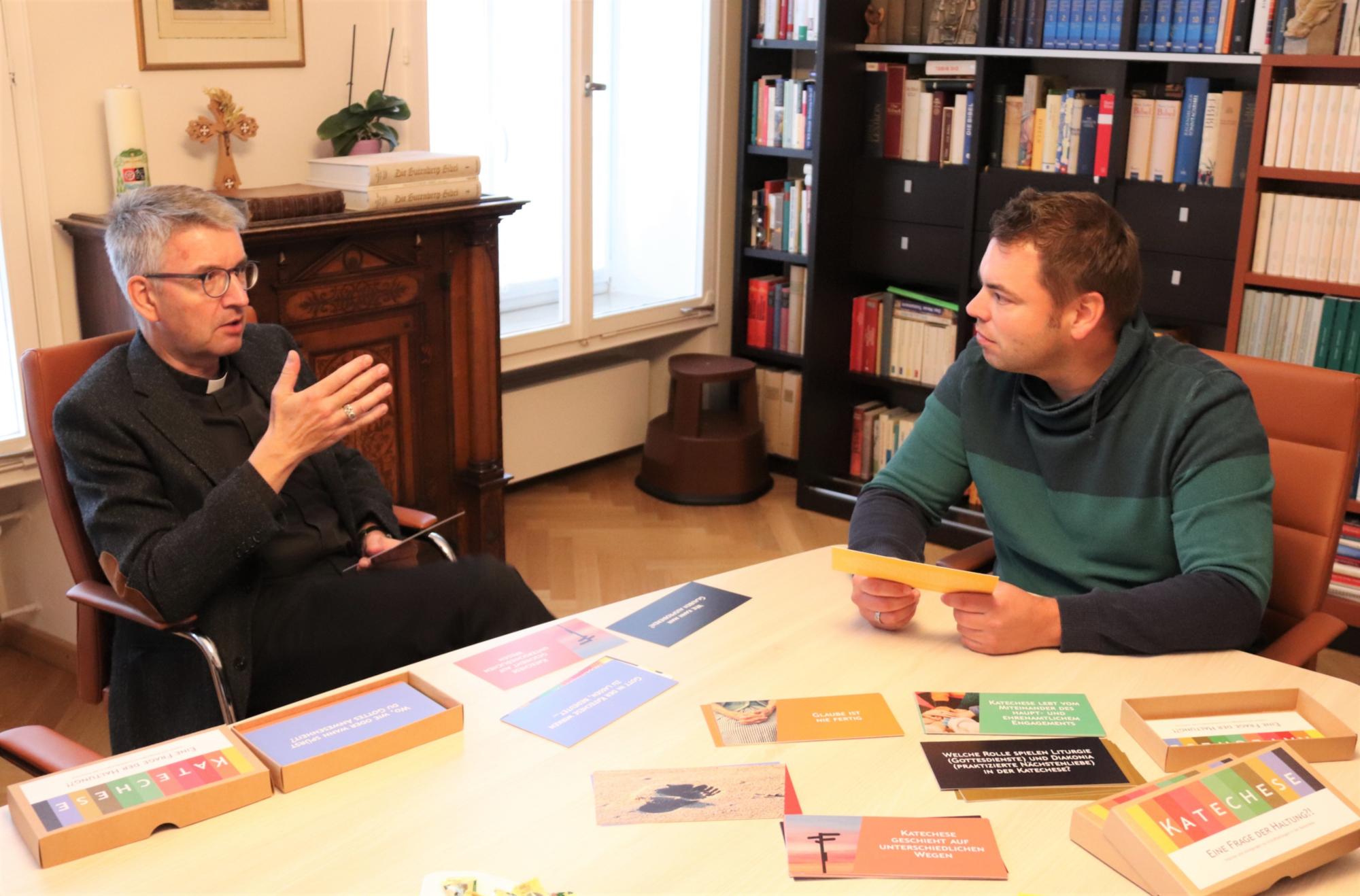 Bischof Peter Kohlgraf und Aaron Torner, Referent für Katechese im Bistum Mainz, tauschen sich über ein neues Kartenset mit dem Titel „Katechese – Eine Frage der Haltung?!“ aus