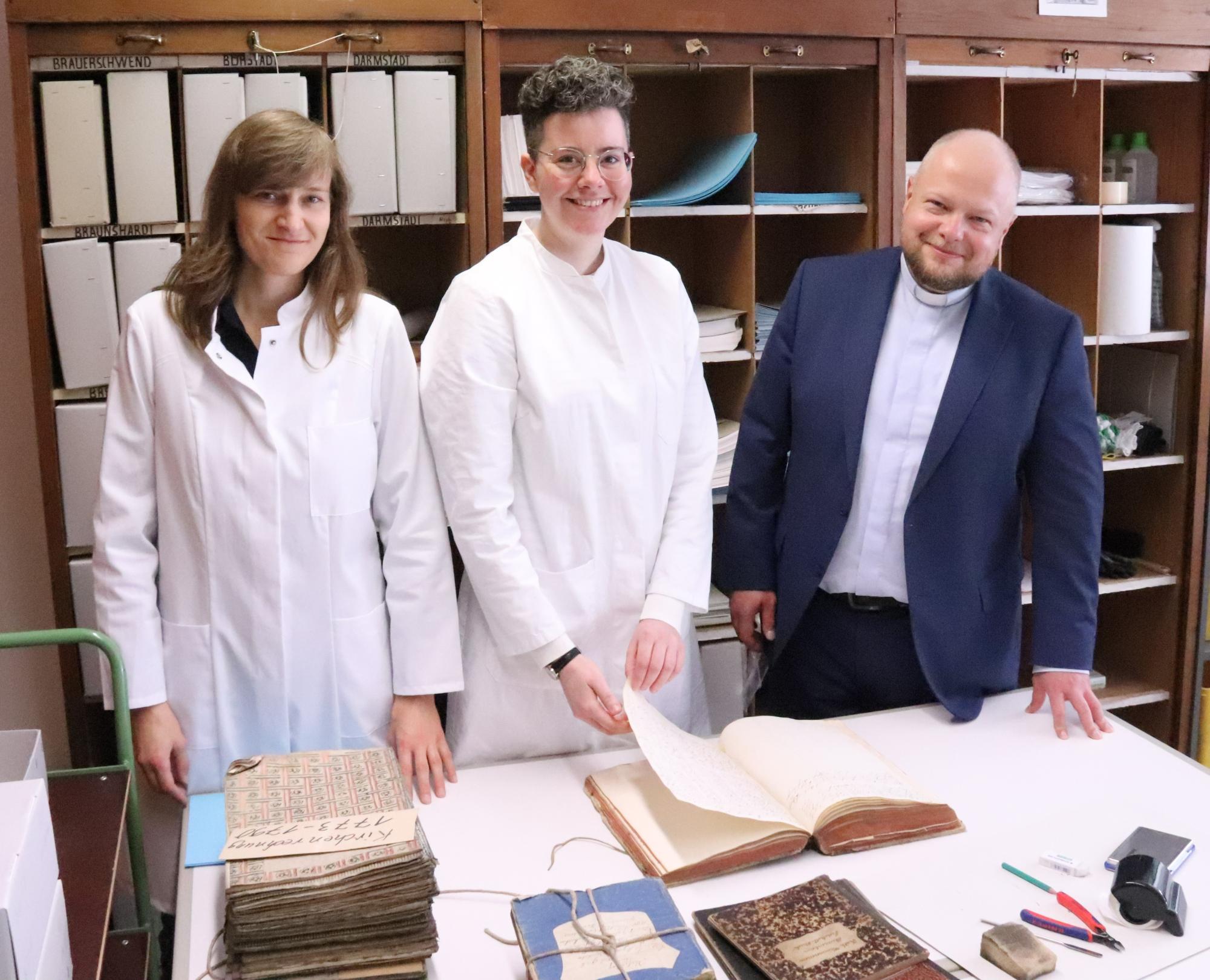 Generalvikar Sebastian Lang (rechts) informiert sich bei Lotte Kosthorst (links) und Eva Grabietz (Mitte) über die Arbeit an den Kirchenbüchern (c) Bistum Mainz/Hoffmann