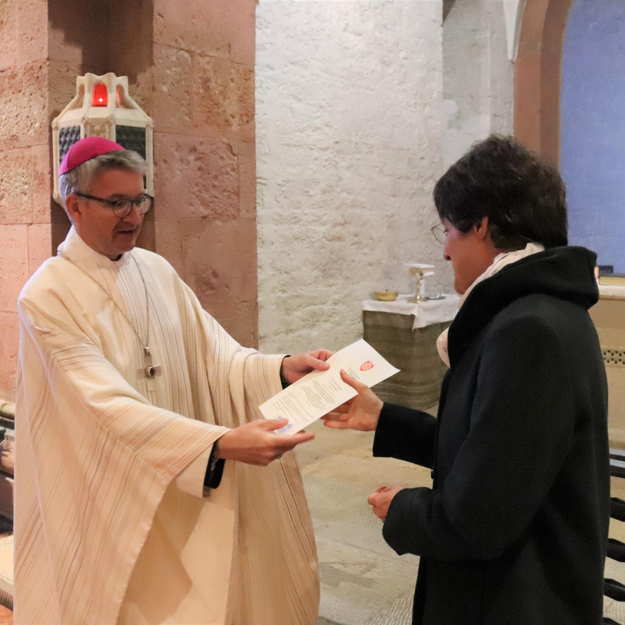 Bischof Peter Kohlgraf überreicht Dr. Juliane Reus ihr Dekret für ihre neue Aufgabe als Referentin am Institut für Spiritualität