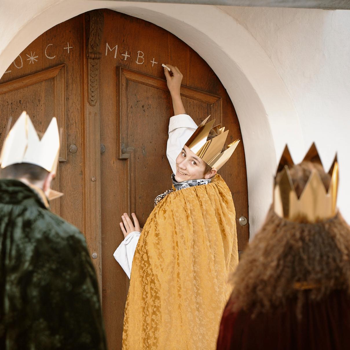 Sternsinger schreiben den Segen an die Haustür