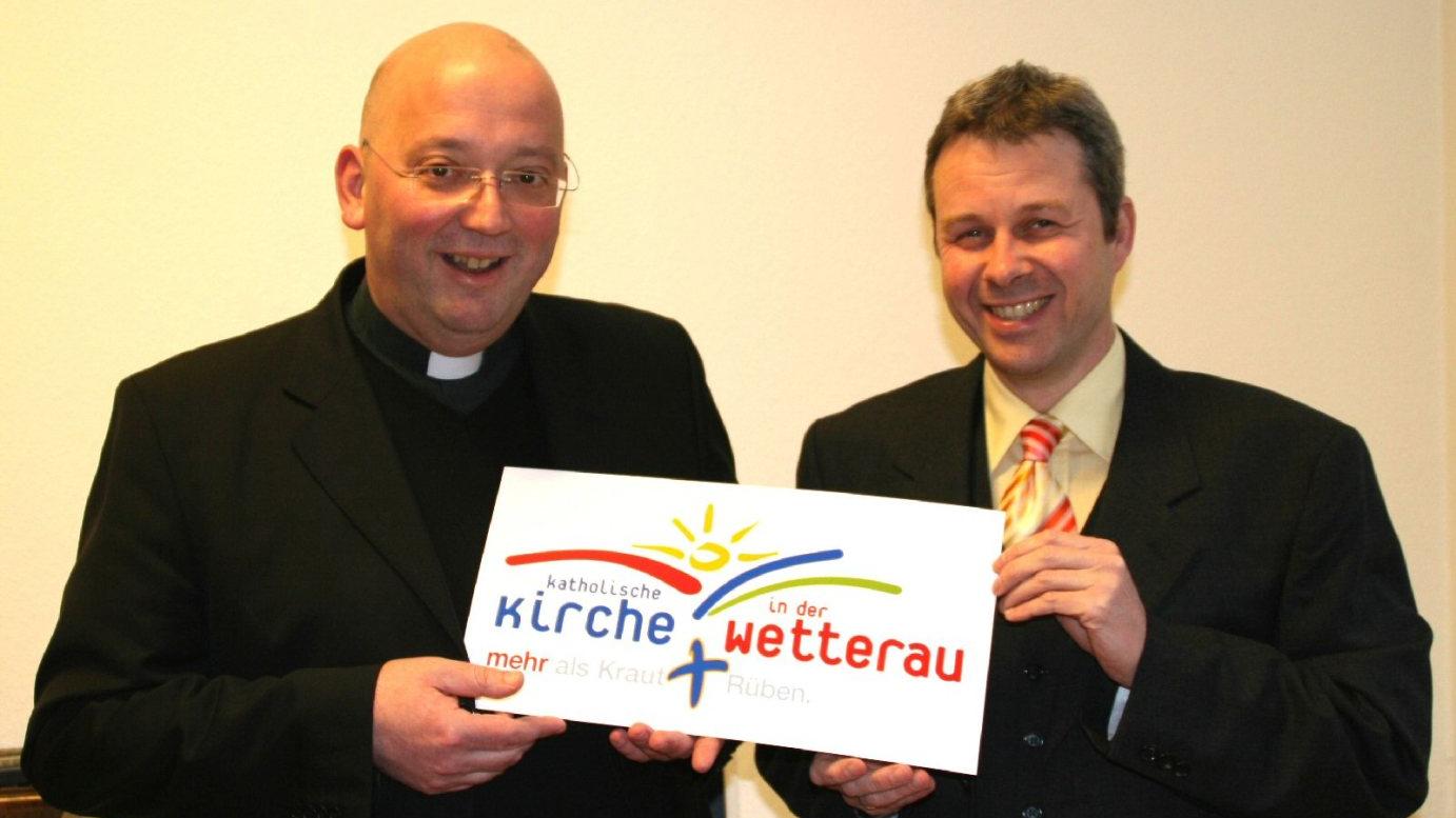 Butzbach, 20.12.2006: Pfarrer Hans-Joachim Wahl (l.), Dekan des Dekanates Wetterau-West, und Gregor Rettinghaus, Leiter der Projektgruppe der katholischen Kirche beim Hessentag 2007, stellen das Logo des Dekanates Wetterau-West für den Hessentag vor.