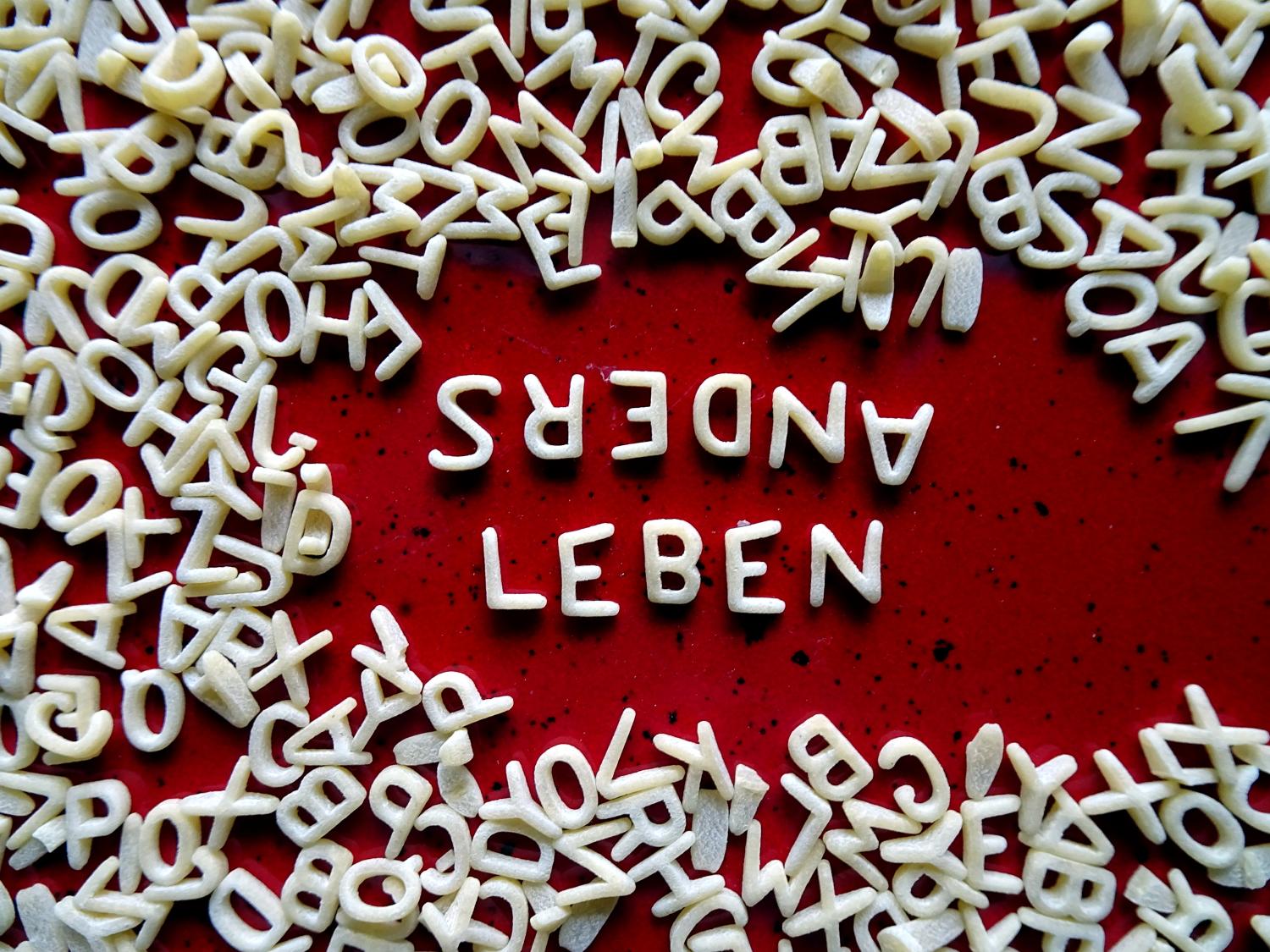 Die Worte 'anders leben' aus Nudelbuchstaben gebildet liegen auf dem Tisch