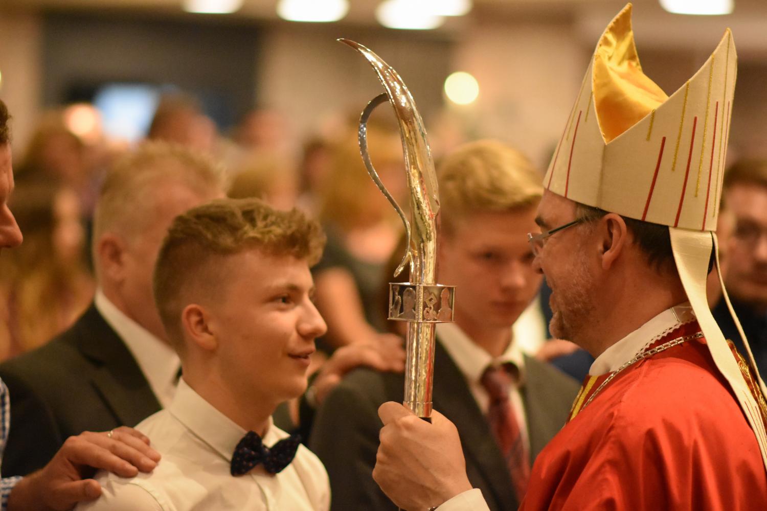 Bischof firmt jungen lächelnden Mann