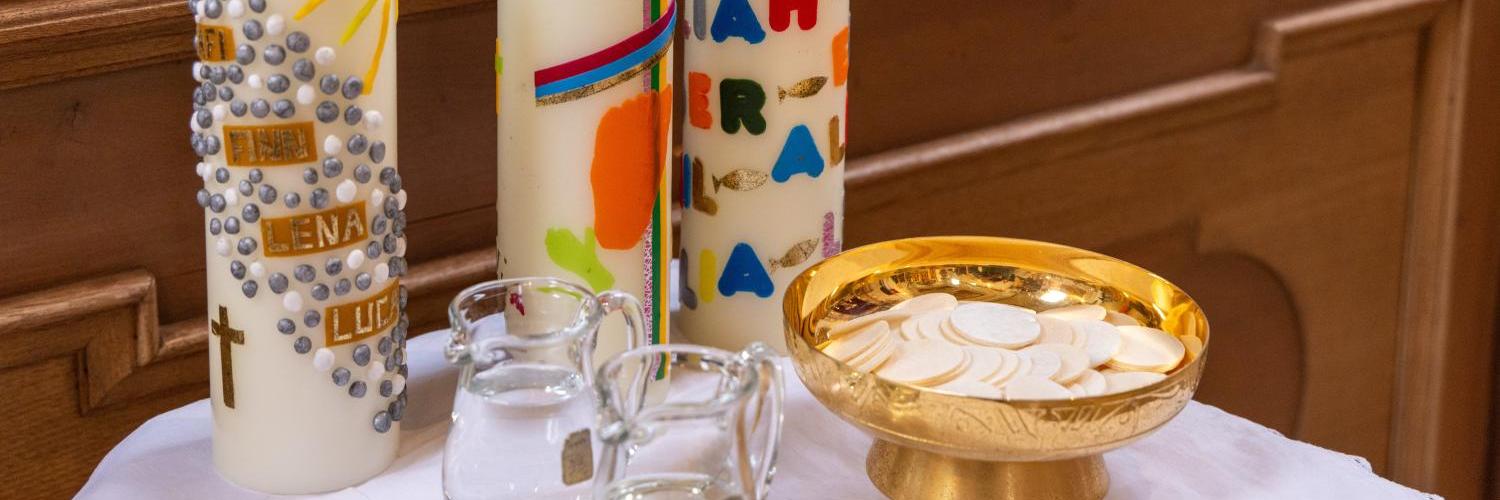 Hostien, Wein und Wasser und drei Gruppenkerzen stehen für einen Erstkommuniongottesdienst bereit