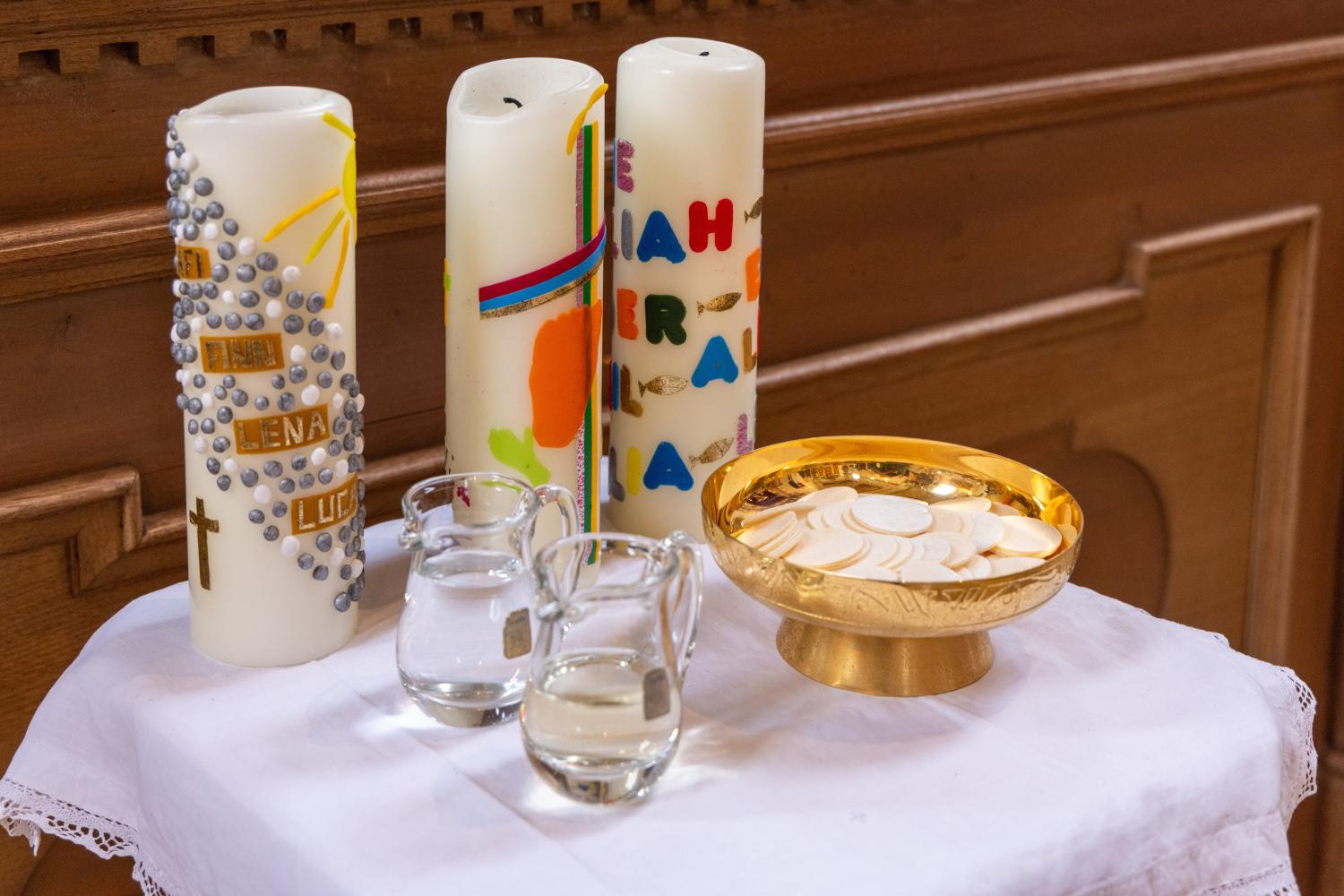 Hostien, Wein und Wasser und drei Gruppenkerzen stehen für einen Erstkommuniongottesdienst bereit