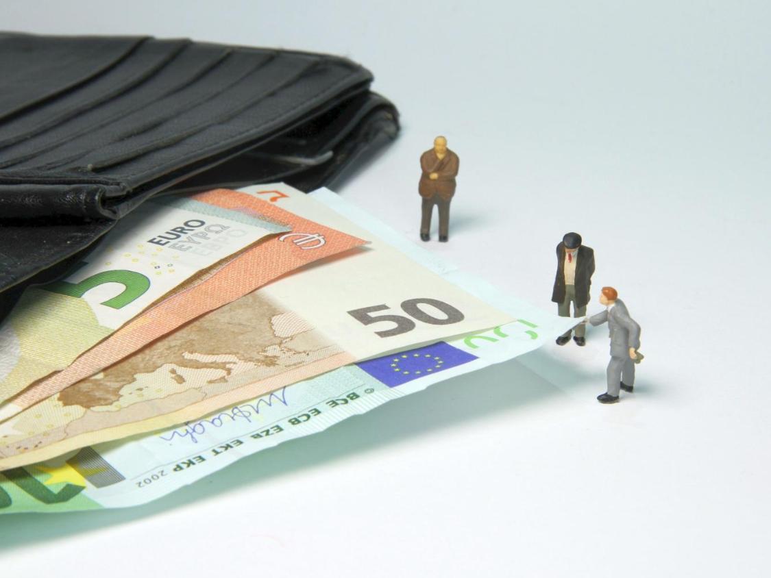 Miniaturfiguren neben Geldscheinen