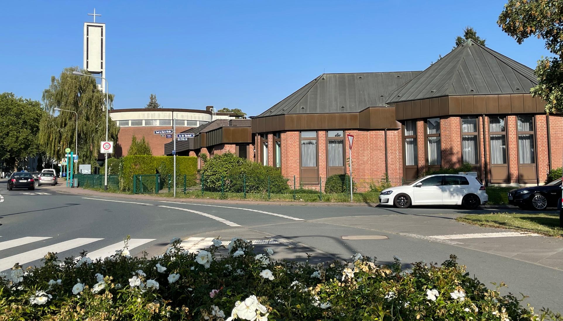Blick auf Kirche und Pfarrgemeindehaus in Nieder-Eschbach, Blumen im Vordergrund