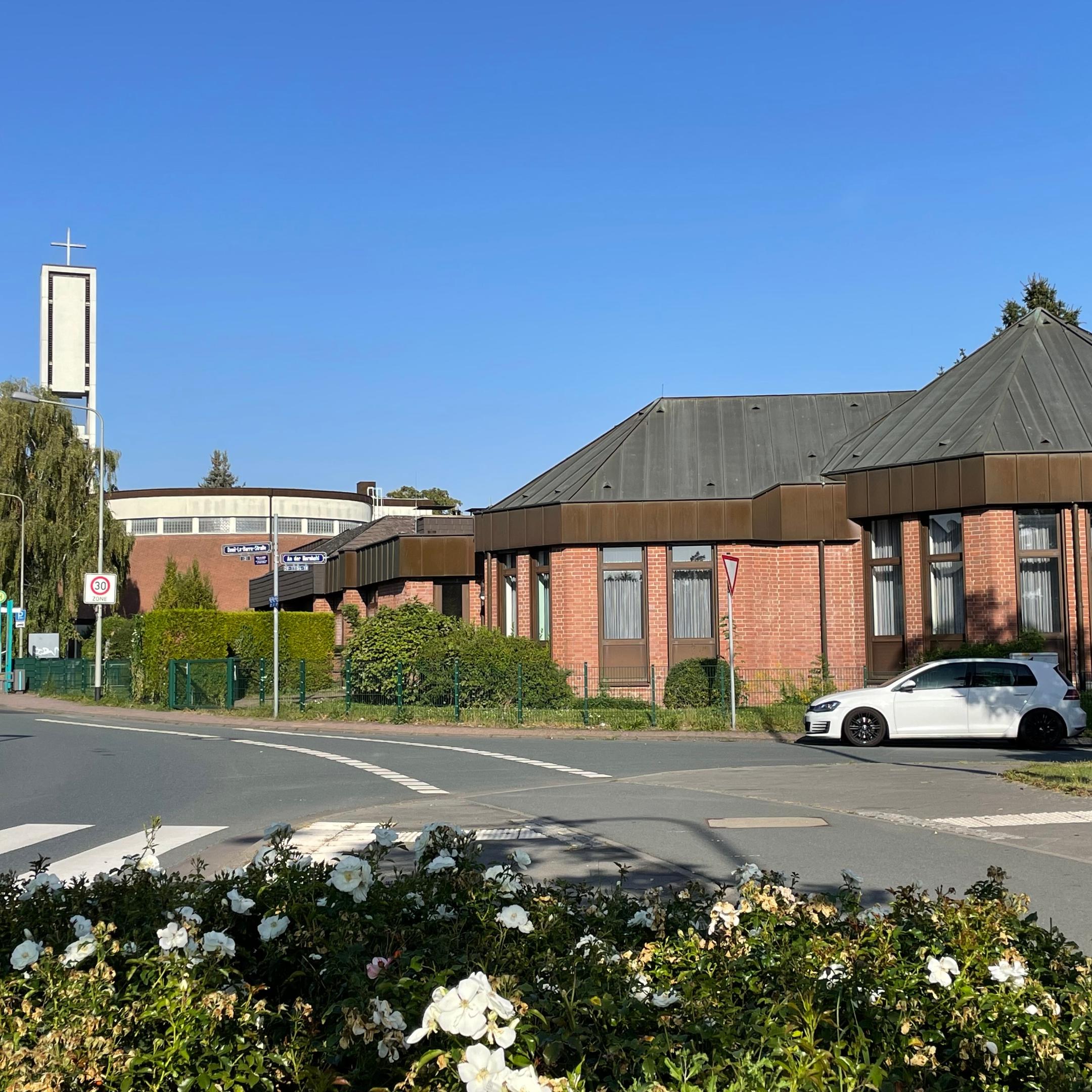 Blick auf Kirche und Pfarrgemeindehaus in Nieder-Eschbach, Blumen im Vordergrund