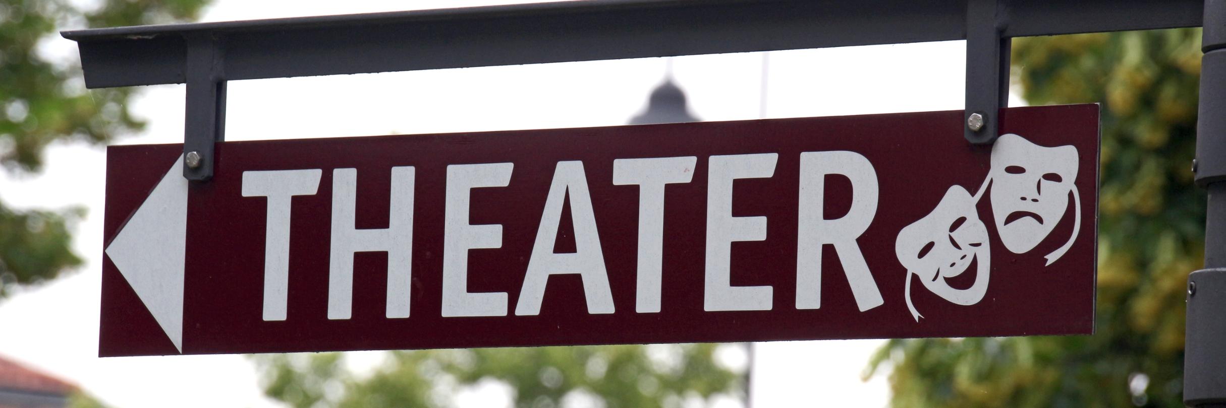 Schild mit Schriftzug Theater und zwei stilisierte Theatermasken