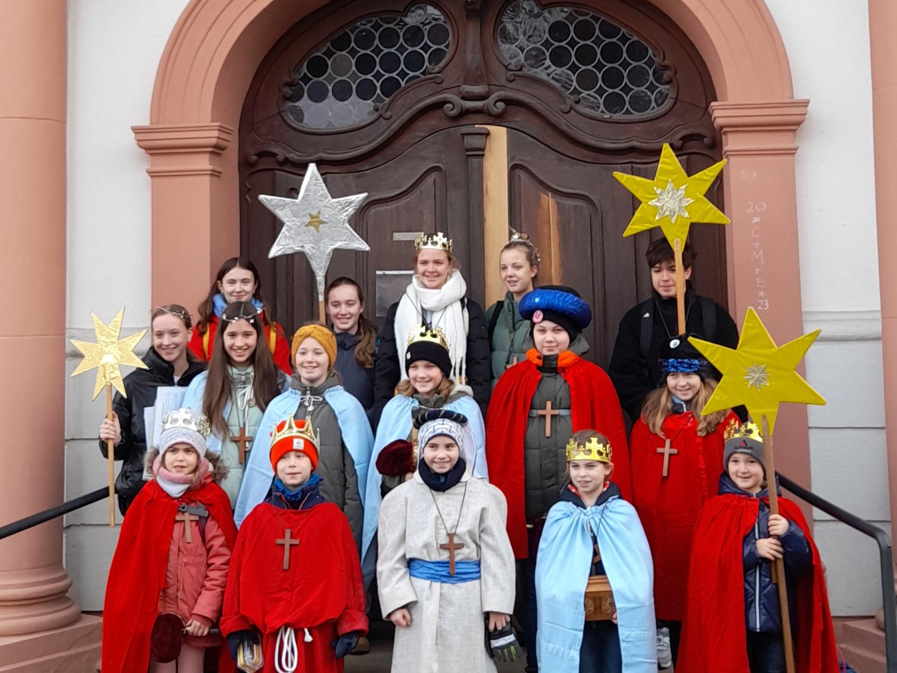 Sternsinger-Gruppe steht vor einer Kirchentür
