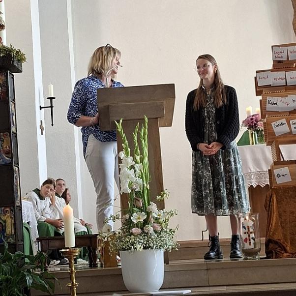 Menschen stehen im Altarraum einer Kirche und begrüßen eine neue Pastoralreferentin.