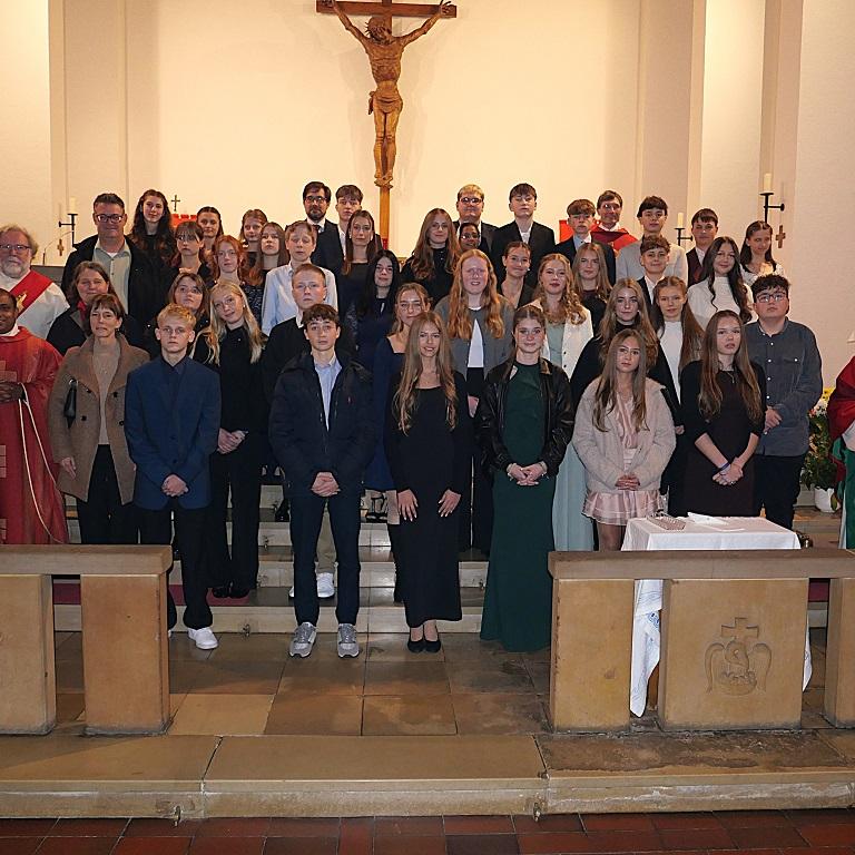 35 Jugendliche in einem Kirchenraum mit Bischof und weiteren Geistlichen und Erwachsenen.