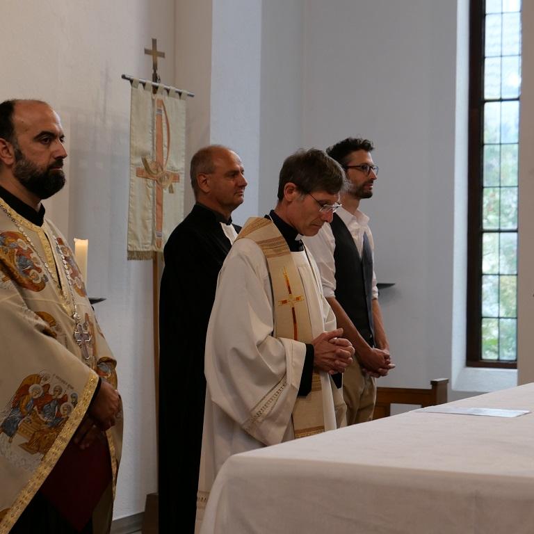 Vier Pfarrer in unterschiedlichen Gewändern an einem Altar.