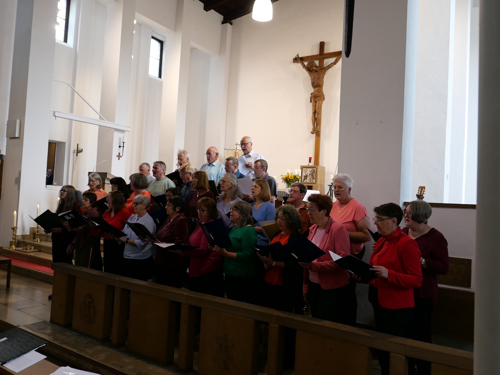 Gemeinsam sangen Mitglieder verschiedener Gemeinden im Projektchor. Frauen und Männer singen zusammen in einem Chor in einer Kirche